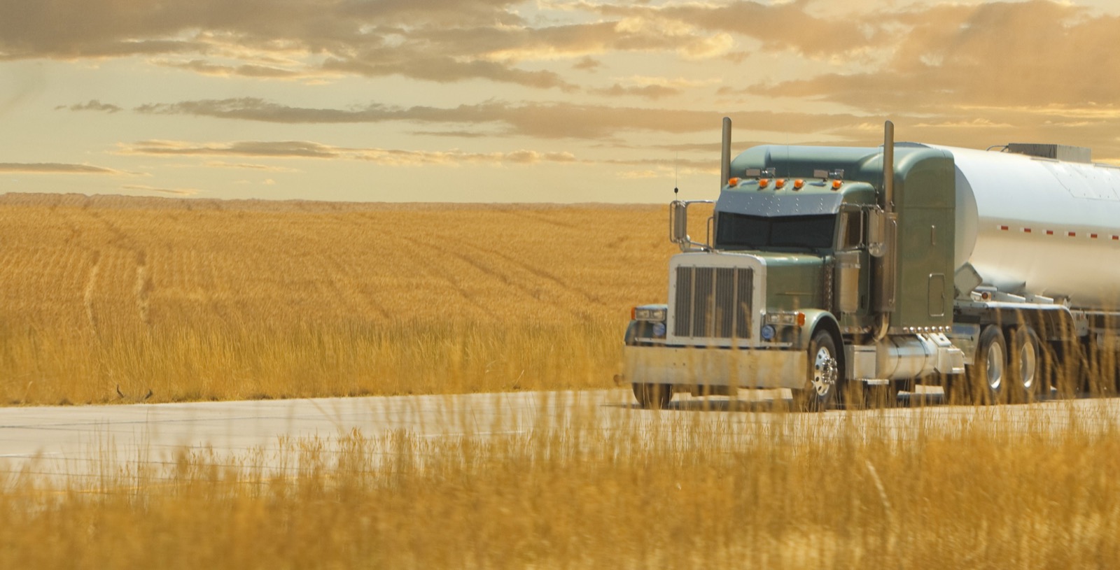 Fuel tanker truck driving past a wheat field